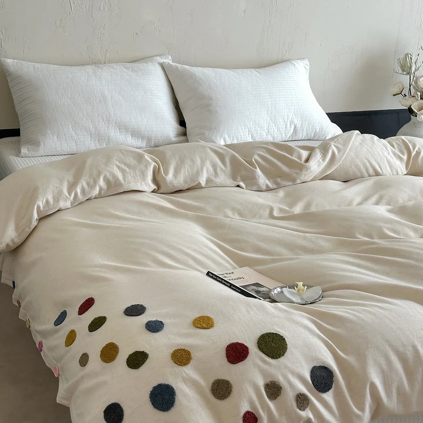 Cozy beige duvet cover with colorful polka dots on bed, white pillows, minimal bedroom decor