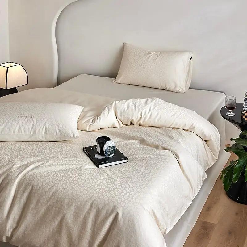 600TC Egyptian Cotton Diamond Wave Pattern Duvet Set in bone color with a candle at the foot of the bed on top of a coco chanel fashion magazine  - Fluffyslip